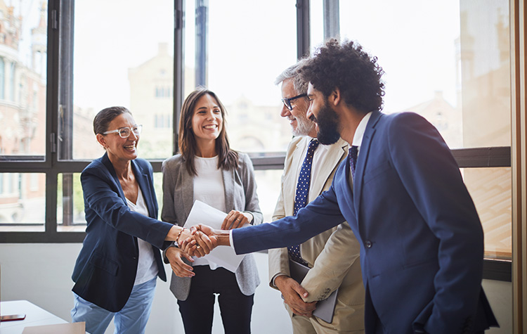 Employees shake hands while laughing