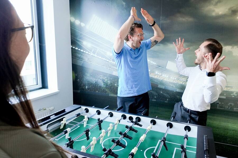 Mitarbeitende spiele Kicker und freuen sich