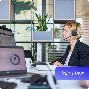 Mitarbeiterin sitzt an ihrem Arbeitslplatz und telefoniert mit Headset